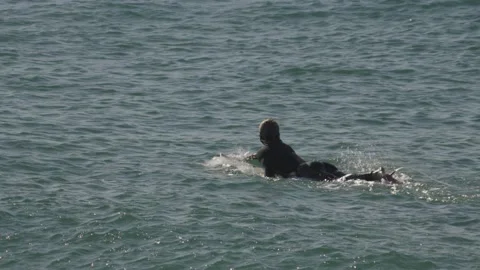 Surfer paddling on surfboard on waves. Close up slow motion shot Stock Footage 231478656
