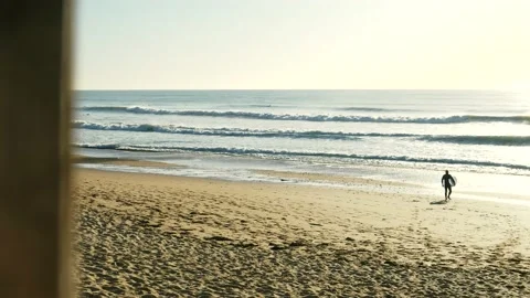Surfer preparig on beach with heavy waves rolling in 動画素材 220038625