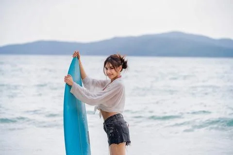 Surfer preparing on the beach with a blue surfboard during sunny weather an.. Stock Photos