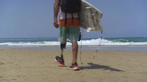 Surfer with prosthesis walking on the beach Stock Footage 142618675