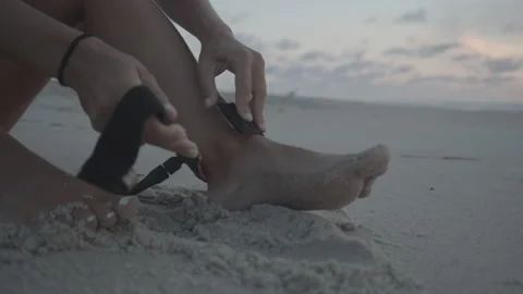 Surfer puts ankle strap on beach Video stock 140360430