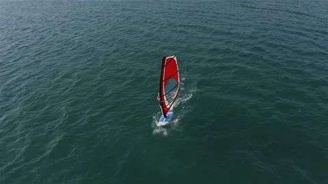 Surfer with a red sail confidently passes the waves Stock Footage 146245632
