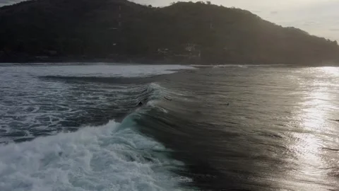 Surfer rides big, pushy shore break surf wave in golden dusk lighting Stock Footage 251607977