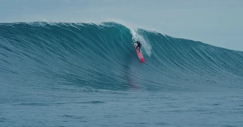 Surfer rides giant blue ocean wave. Shot on RED in 4k. Big wave surfing. Slow mo Stock Footage
