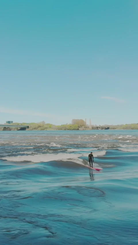 Surfer rides river wave near Habitat 67 building. Montreal, CA Stock Footage 315076853