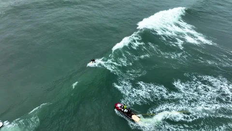 Surfer rides wave after tow-in near Nazaré cliffs Stock Footage 309001675