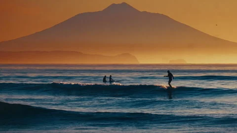 Surfer rides the wave in the ocean with volcano on the background during calm 库存影片 330535873