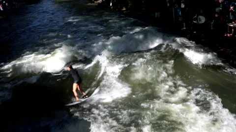 A surfer rides the wave in the stream of the Englischer Garten in Munich. Stock Footage 249252997