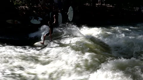 A surfer rides the wave in the stream of the Englischer Garten in Munich. Stock Footage 249253261