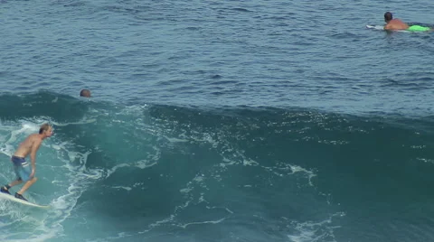 A surfer rides a wave in the surf at the ocean blue in the surf spot. Stock Footage 61205620