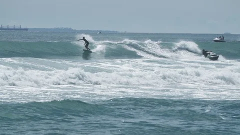 Surfer rides waves in front of ships Stock Footage 93722745