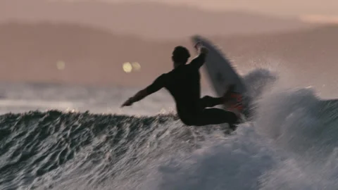 A surfer riding big waves at sunset Stock Footage 264147991