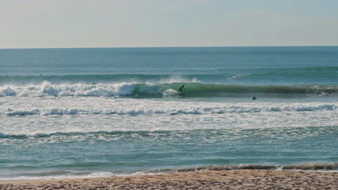Surfer riding on blue Atlantic Ocean waves on a beautiful sunny day Stock Footage 130626332