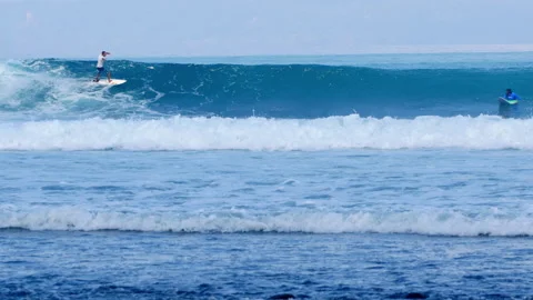 Surfer riding blue ocean wave with another waiting in background Stock Footage 336875336