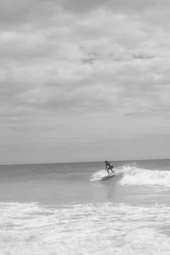 Surfer Riding a Wave Under a Cloudy Sky Foto stock