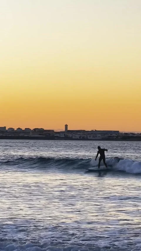 Surfer riding wave under orange sky Stock Footage 331659738