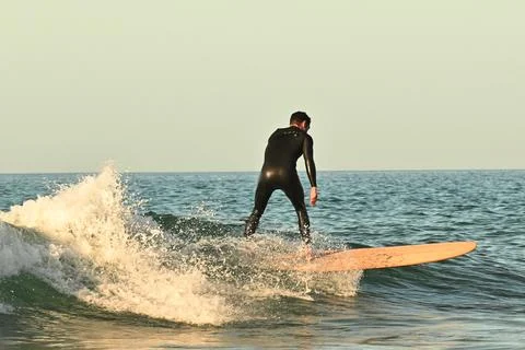 Surfer riding waves along dramatic coastline (1) ,27/08/2025 Fotos Stock