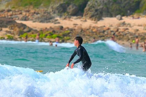Surfer riding waves along dramatic coastline (20) ,27/08/2025 Stock Photos