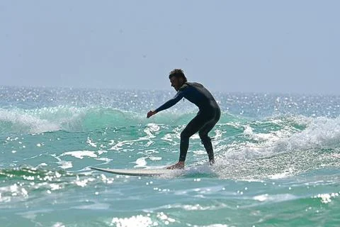 Surfer riding waves along dramatic coastline (26) , 27/08/2025 Stock Photos