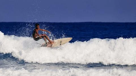Surfer school. A young guy learning to stand on a surfboard. Surfer on the wa Stock Photos