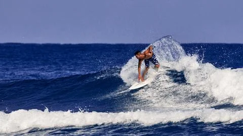 Surfer school. A young guy learning to stand on a surfboard. Surfer on the wa Stock Photos