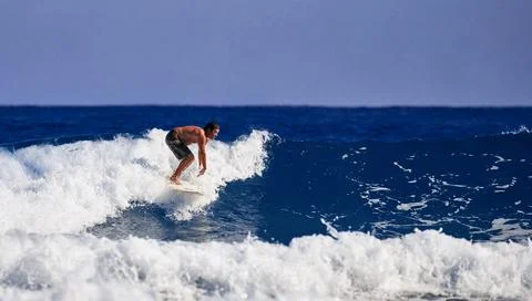 Surfer school. A young guy learning to stand on a surfboard. Surfer on the wa Stock Photos