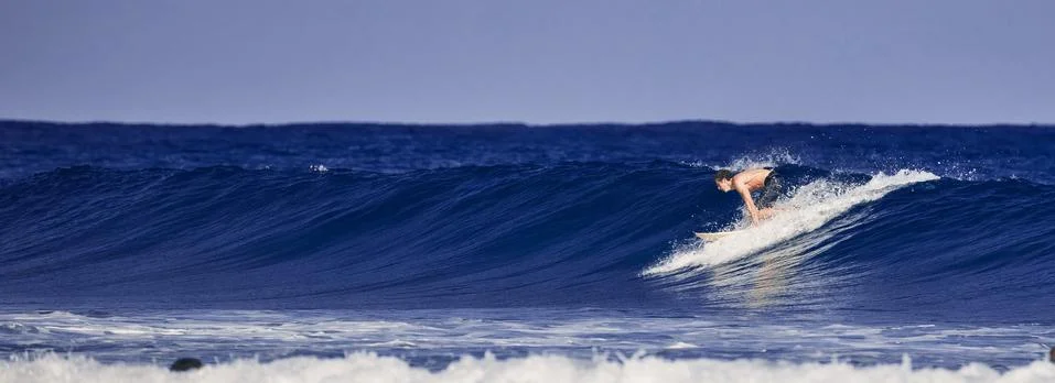 Surfer school. A young guy learning to stand on a surfboard. Surfer on the wa Stock Photos