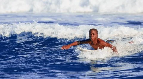 Surfer school. A young guy learning to stand on a surfboard. Surfer on the wa Stock Photos