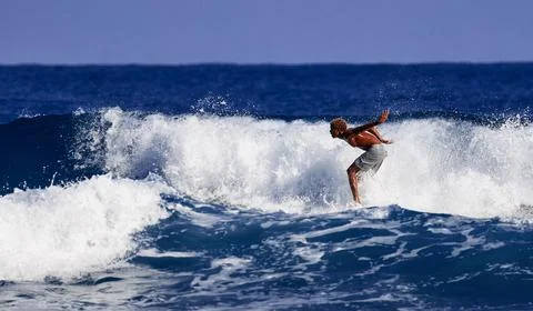 Surfer school. A young guy learning to stand on a surfboard. Surfer on the wa Stock Photos