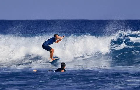 Surfer school. A young guy learning to stand on a surfboard. Surfer on the wa Stock Photos