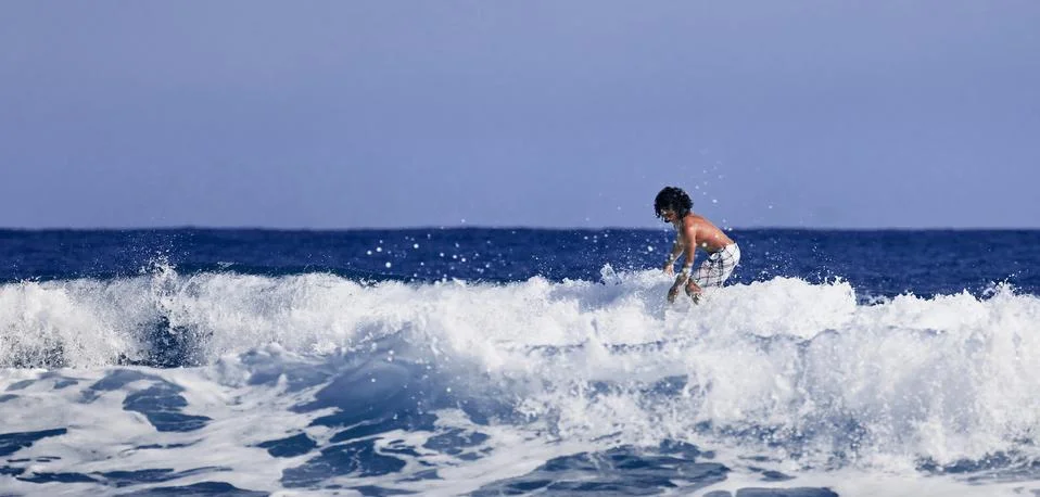 Surfer school. A young guy learning to stand on a surfboard. Surfer on the wa Stock Photos