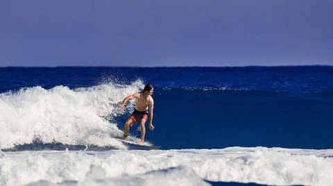 Surfer school. A young guy learning to stand on a surfboard. Surfer on the wave Stock Photos