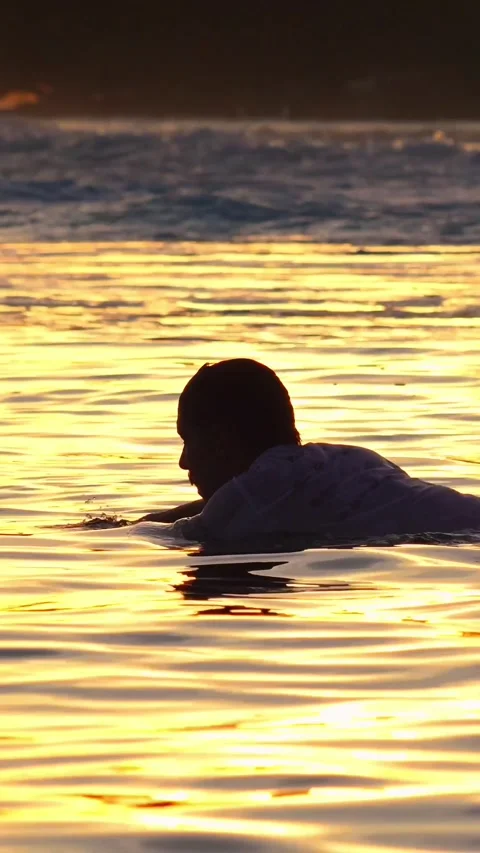 Surfer in sea at sunset time, vertical video Stock Footage 295758955
