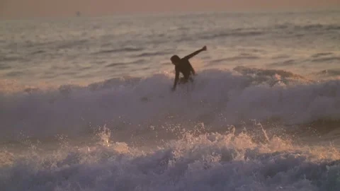 Surfer shredding through rough waves wipes out slow motion sunset Stock Footage 146628400