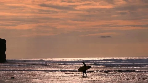 Surfer in silhouette walking with long surf boards at sunset on tropical beach Stock Footage 74854225