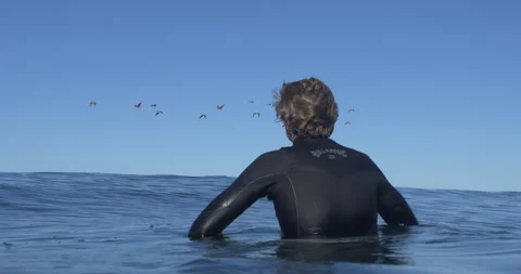 Surfer Sits in Ocean Stock Footage 262120029