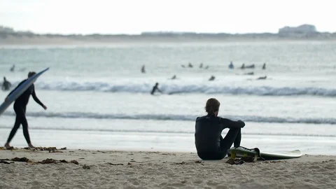 Surfer sitting at the beach Stockbeeldmateriaal 111139573