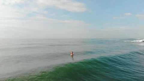Surfer Sitting on Board in Open Ocean, Calm Waves Rolling In Stock Footage 303521487