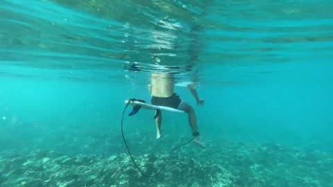 Surfer sitting on a surfboard in Indian ocean. Underwater shot Stock Footage 294167352