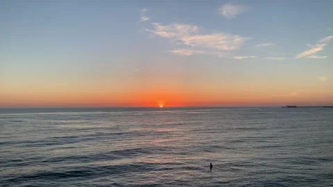 Surfer sitting on surfboard in the ocean watching the sunset. Video stock 244948249