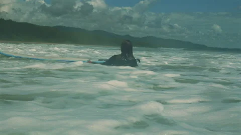 Surfer sitting on surfboard in ocean waves with distant coastline and Video stock 285074729