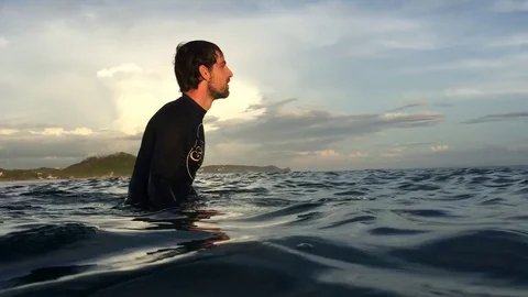Surfer sitting on surfboard waiting for waves Stock Footage 84893978