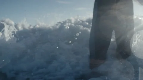 Surfer splashing through waves with sunshining through Stock Footage 169312808