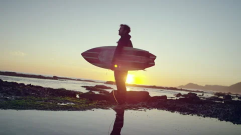 Surfer standing on the beach in the evening Stock Footage 279002070