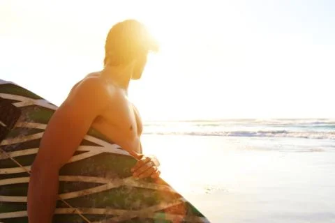 Surfer standing on beach looking at waves during sunset Foto stock