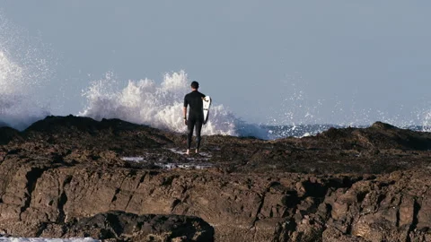 Surfer Standing while Waves are hitting the Coast Stock Footage 264146118