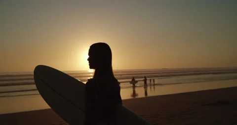 Surfer stands alone on beach during sunset Vidéo 138338185