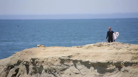 Surfer stretching on a cliff at the beach Stock Footage 64257067