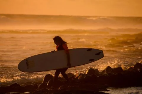 Surfer at sunset on a calm ocean Stock Photos