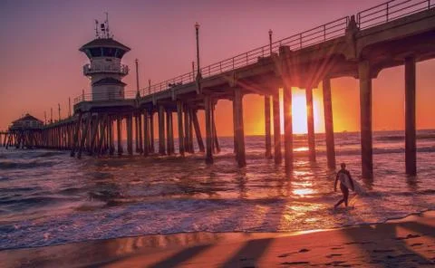 Surfer at sunset in front of the Huntington Beach Pier Stock Photos